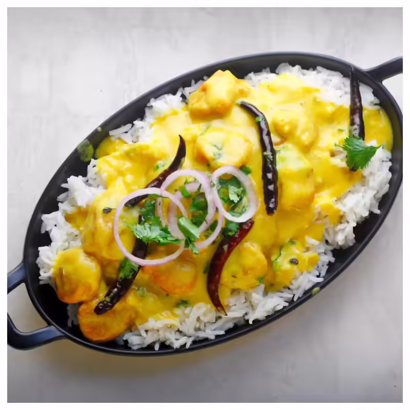 Delicious Punjabi Kadhi Chawal served in a black bowl topped with green chilies